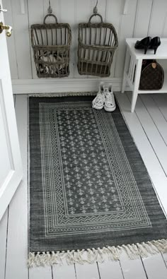 an image of a rug on the floor in front of a door with two baskets next to it