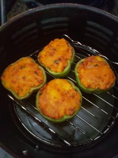 four green peppers sitting on top of an open grill with cheese in the middle,