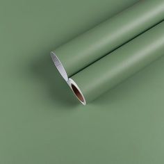 a roll of light green colored paper on a green surface with a white tip sticking out of it