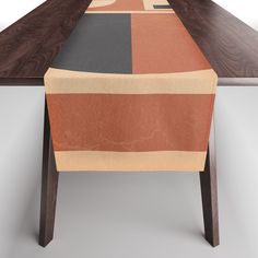 the table is made up of wood and has an orange, black, gray, and red design on it