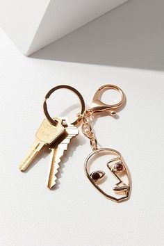 two keys are attached to each other on a keychain with a face in the middle