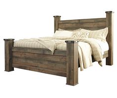 a wooden bed with white sheets and pillows