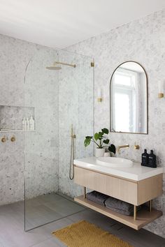 a bathroom with a sink, mirror and shower in it's corner area next to a rug on the floor