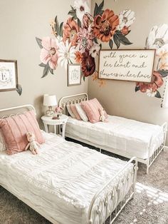 two twin beds with pink and white pillows in a girls'room decorated with flowers