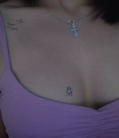 a woman wearing a purple top with a cross tattoo on her chest