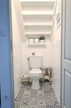 a white toilet sitting inside of a bathroom next to a window on top of a tiled floor