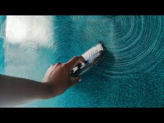 a hand holding a cell phone next to a blue pool with water swirling around it