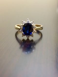 DeKara Designs Collection Metal- 14K Yellow Gold, .583. Stones- 1 Oval Blue Sapphire 1.14 Carats, 10 Round Diamonds G-H Color VS2 Clarity, 0.30 Carats. Size- Ring is a 5 3/4, and could be sized up or down at no additional cost! Handmade 14K Yellow Gold Sapphire and Diamond Ring. This ring is inspired by the Art Deco era with an enticing fiery oval shaped blue sapphire. The sapphire is set in between 4 prongs. The sapphire has a halo of prong set 10 round diamonds surrounding them which brings ou Gold Sapphire Diamond Ring With Halo Design, Gold Sapphire Ring With Halo Design, Formal 14k Gold Sapphire Ring With Halo Design, Gold Sapphire Cluster Ring With Brilliant Cut, Gold Oval Sapphire Cluster Ring, Gold Sapphire Oval Cluster Ring, Oval Sapphire Cluster Ring In Gold, Blue 14k Gold Diamond Ring With Halo Design, Yellow Gold Sapphire Ring With Halo Design For Wedding