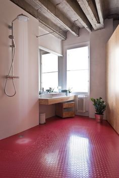 a bathroom with red flooring and wooden cabinets in the corner, next to a window