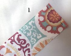 a piece of fabric with an orange and blue flower pattern on it, next to a sewing needle