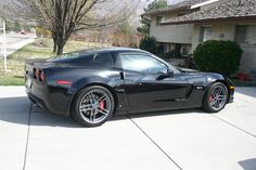 a black sports car parked in front of a house