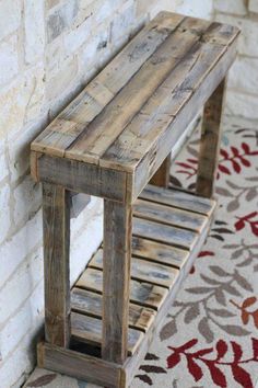 a wooden bench sitting on top of a rug next to a white brick wall and floor