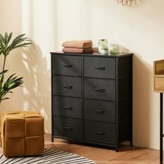 a black dresser sitting next to a plant in a room with a rug on the floor