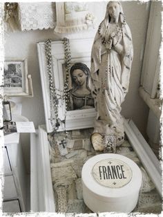 a white statue sitting on top of a table next to a framed photo and other items