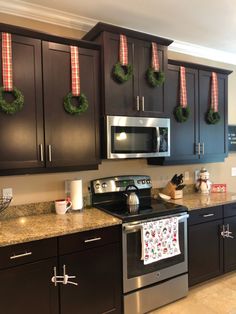 a kitchen decorated for christmas with wreaths hanging on the cabinets and stove top oven