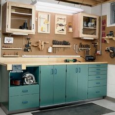 a workbench with lots of tools on the wall and cupboards above it