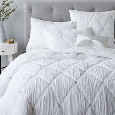 a bed with white comforter and pillows in a bedroom