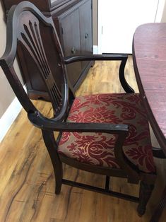 a wooden chair sitting on top of a hard wood floor next to a table and cabinet