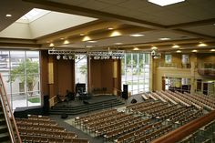 an empty auditorium with rows of seats and stage lights on the ceiling, looking out onto the courtyard