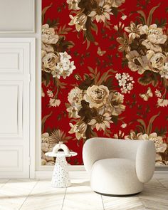 a white chair sitting in front of a red wall with flowers on it's side