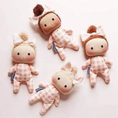 four little dolls are laying on the floor together, one is wearing a white and brown checkered outfit