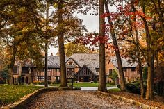 a large house surrounded by trees with leaves on the ground