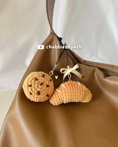 two crocheted cookies hanging from a brown purse