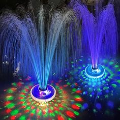 two fountains with colored lights in the middle of it and water spouting from them