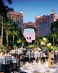 an outdoor dining area with tables, chairs and palm trees in front of the hotel