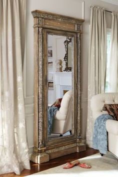 a mirror sitting on top of a wooden floor next to a white couch in a living room