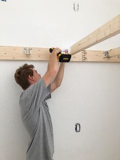 a man is working on the ceiling in his room with wood planks attached to it