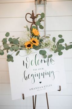 a welcome sign with sunflowers and greenery