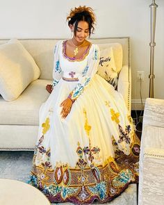 a woman sitting on top of a couch in a white dress