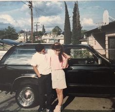 two people standing in front of a black car