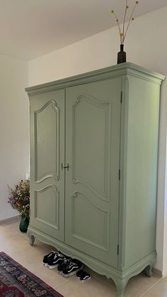 a green armoire sitting in the middle of a living room next to a rug