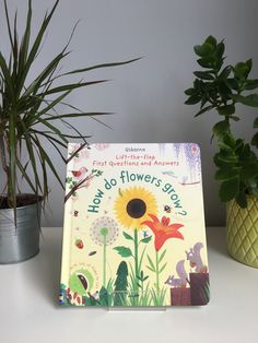 a children's book sitting on top of a table next to two potted plants