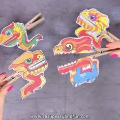 two hands holding chopsticks with different colored dragon stickers on top of them