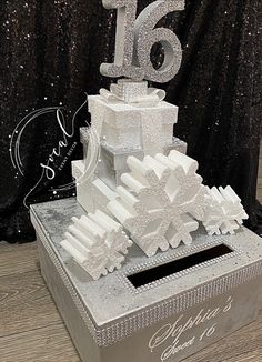 a large white cake sitting on top of a box covered in snowflakes