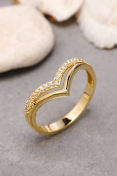 a yellow gold ring with diamonds on the inside and outside, sitting next to seashells