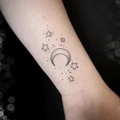 a small wrist tattoo with stars and the moon