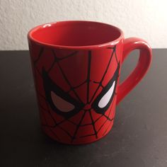 a red spider man mug sitting on top of a table