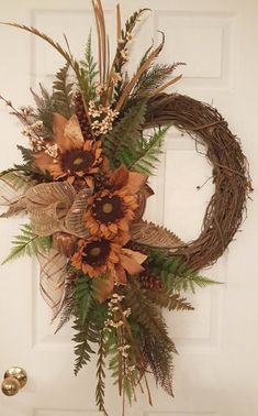 a wreath with sunflowers and ferns hanging on a door