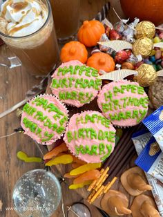 several decorated cookies sitting on top of a wooden table next to drinks and candies