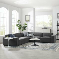 a living room filled with lots of furniture next to two large windows and a rug on the floor