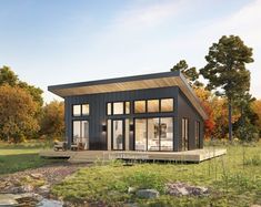 a small house sitting on top of a lush green field next to a forest filled with trees