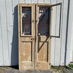 an old wooden door with bars on the top and bottom, in front of a white building