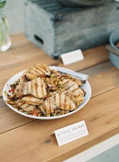 a plate full of grilled chicken sitting on a table next to other food items