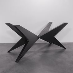 a black sculpture sitting on top of a cement floor next to a white wall in an empty room