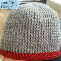 a close up of a person wearing a knitted hat with a red stripe on it