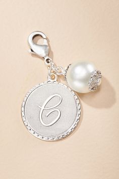 a pearl charm with the letter g on it